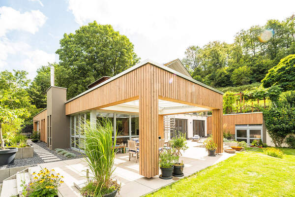 Modernes Einfamilienhaus mit Holzfassade, großer Terrasse und Garten im Grünen.