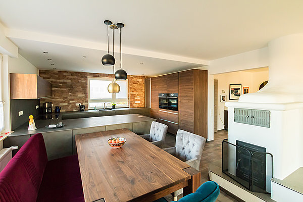 Moderne Einbauküche mit Essbereich, Kaminofen und Holzdekor im offenen Wohnkonzept.